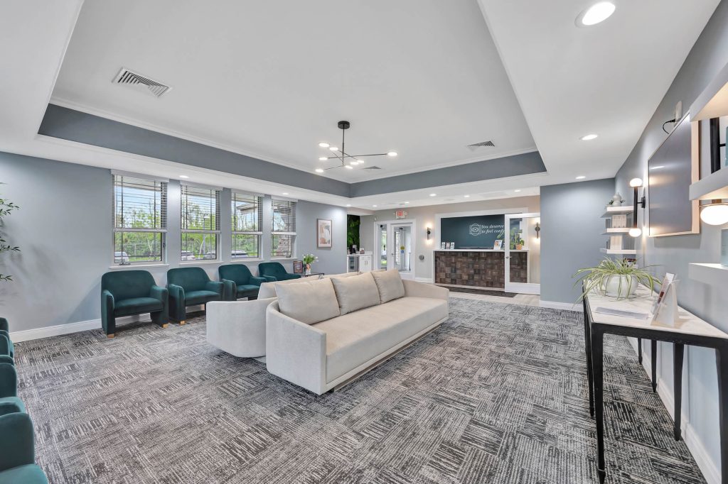 Modern clinic waiting room with a cream sofa and teal armchairs.