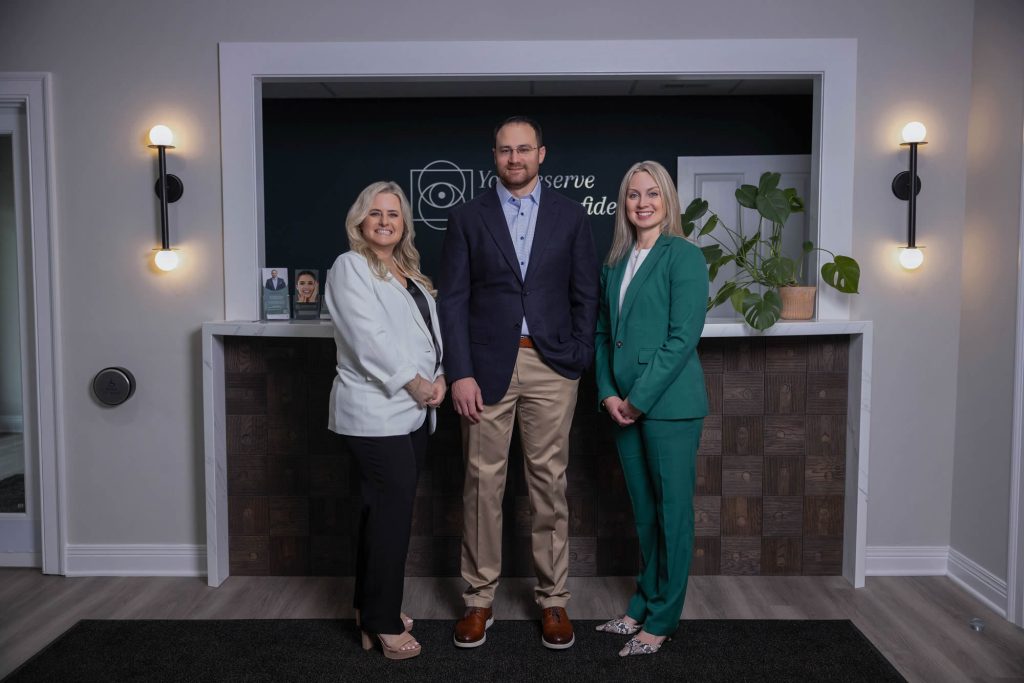 Three medical professionals in business attire posing at the reception.