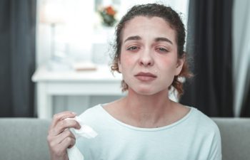 Tears after sneezing. Mature green-eyed woman having much tears after sneezing because of allergy